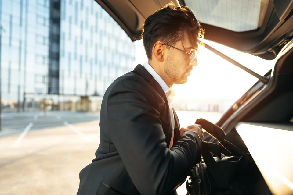 Un voyageur prépare ses bagages près du coffre d’une voiture