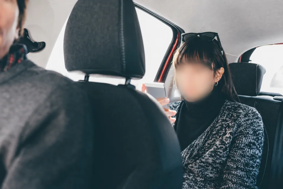 Une passagère consulte son téléphone à l’arrière d’une voiture
